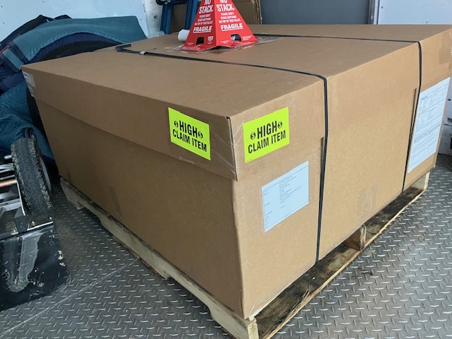 Boxed furniture item loaded in a vehicle with handling labels