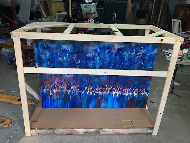 Blue framed artwork secured inside a wood support frame