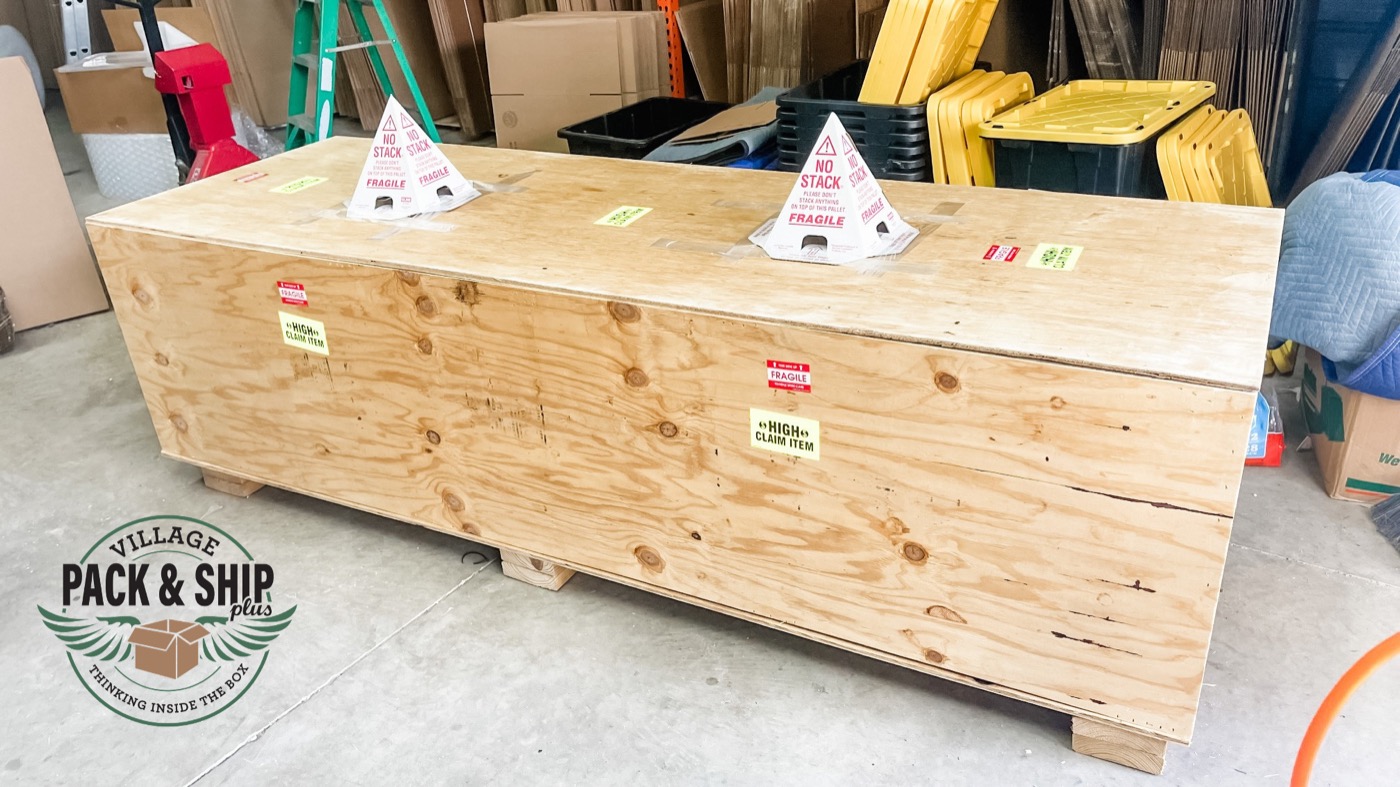 Long wood crate staged with handling labels in a workshop