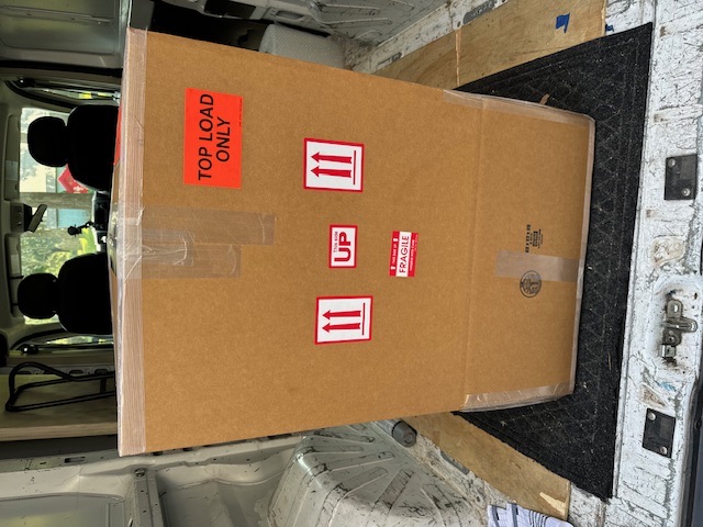 Tall boxed household item staged inside a moving vehicle