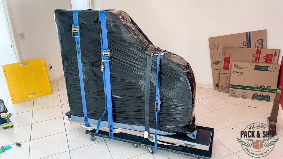 Wrapped grand piano strapped to a moving board
