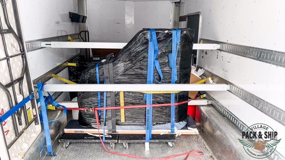 Wrapped grand piano secured inside a moving truck