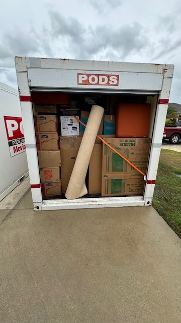 Moving team loading household items into a POD or U-Haul container